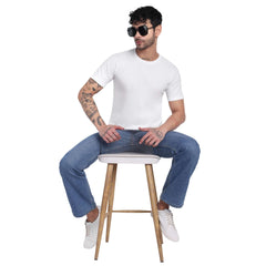 Stylish man wearing a plain white cotton t-shirt seated on a stool, showcasing casual fashion.